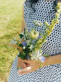 Low section of woman holding flower bouquet