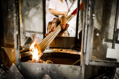 Cropped hand of woman burning incense sticks