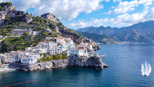 Buildings by sea against sky