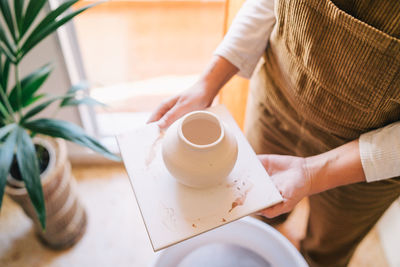 Midsection of woman holding coffee cup on table