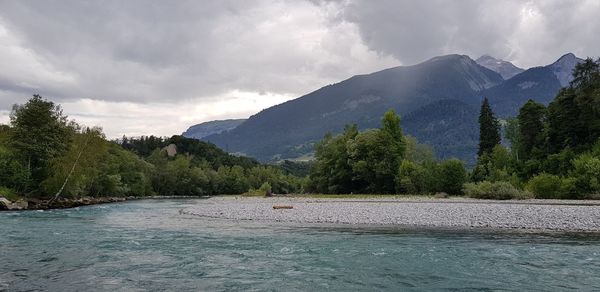 Scenic view of river and mountains against sky