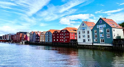 Buildings by river against sky