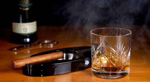 Close-up of whiskey glass with cigar on table