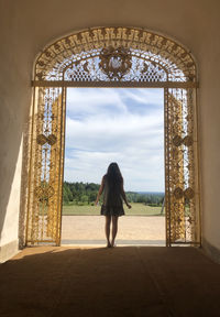 Rear view of woman looking through golden archway 