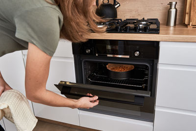 Woman cooking cake in electric oven