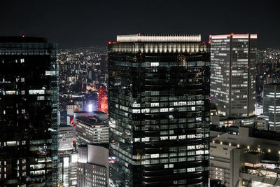 Illuminated buildings in city against sky at night