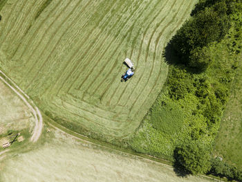 Drone shot of blue tractor with mower cutting fresh green meadow somewhere in austria