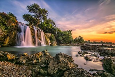 Scenic view of waterfall against sky during sunset