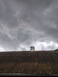 Low angle view of building roof against cloudy sky