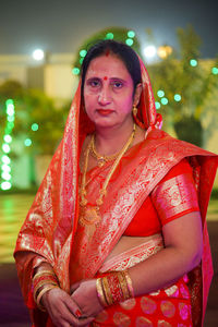 Portrait of young woman standing wearing red saree 