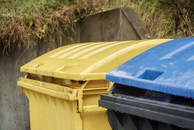 Close-up of yellow and blue garbage cans