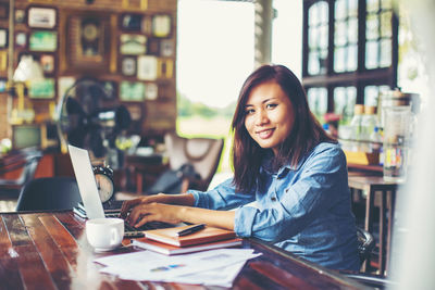 Portrait of young woman sitting on table at cafe