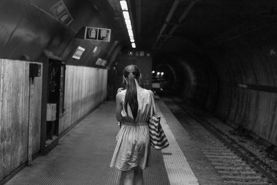 Rear view of woman on illuminated subway platform