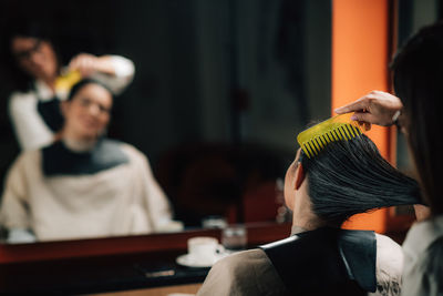 Hairdresser combing customer hair in salon