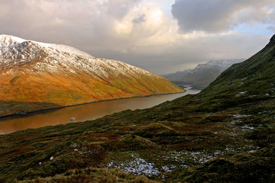 Scenic view of lake by mountains against sky