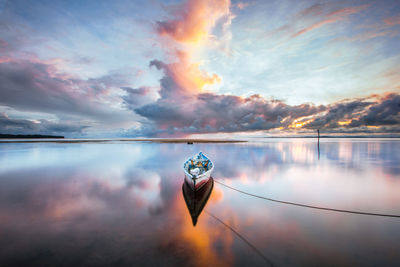 Boat moored in sea at sunset