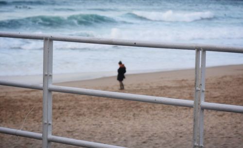 Man walking on railing by sea
