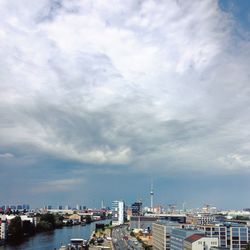 City at waterfront against cloudy sky