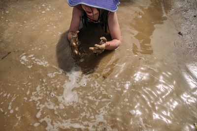 Above shot of young girl playing in muddy water