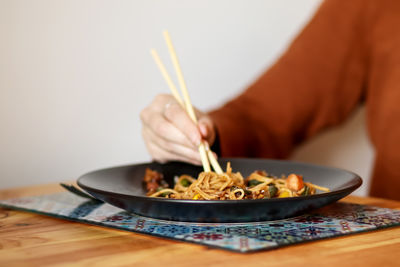 Midsection of man preparing food in plate on table