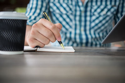 Man with disposable cup using digital tablet outdoors