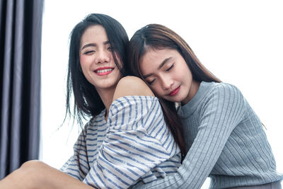 Young woman embracing smiling friend at home