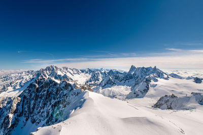 Scenic view of snowcapped mountains against blue sky