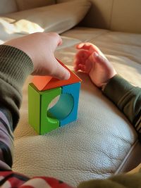 Cropped hands of child playing with toys on sofa