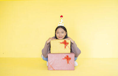 Portrait of a smiling young woman against yellow background