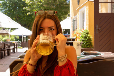 A young woman is drinking a beer in a biergarten in munich