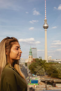 Woman looking away against fernsehturm in city