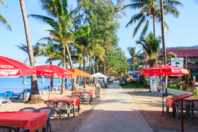 Empty chairs and tables at beach against sky