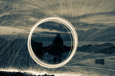 Man spinning wire wool while standing on land against sky