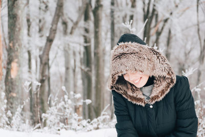 Smiling woman wearing fur coat standing against during winter