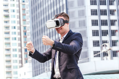 Smiling businessman gesturing while wearing virtual reality in city