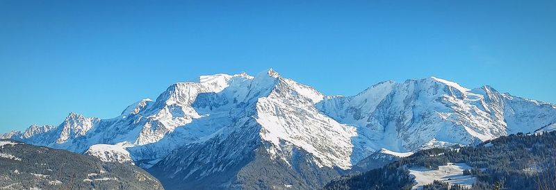 Scenic view of snow covered mountains against clear blue sky