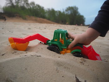 Close-up of hand playing with toy on sand