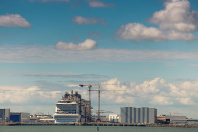 View of factory by sea against sky