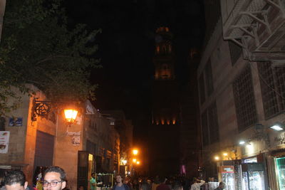 Illuminated street amidst buildings at night