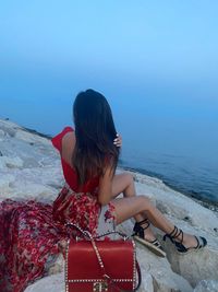 High angle view of woman sitting on rocks against sea