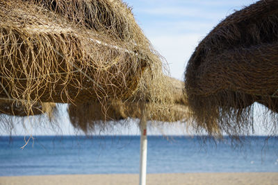 Close-up of hay bales on field against sky