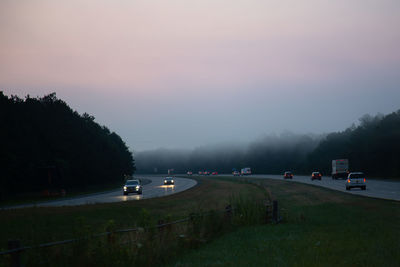 Cars on road against sky at sunset