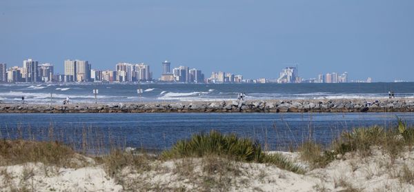 Scenic view of sea and buildings against clear sky