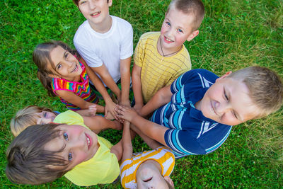 High angle view of siblings sitting on grass