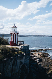 Lighthouse by sea against sky