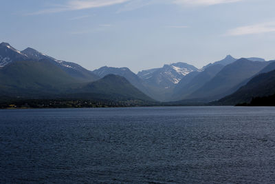 Scenic view of lake by mountains against sky