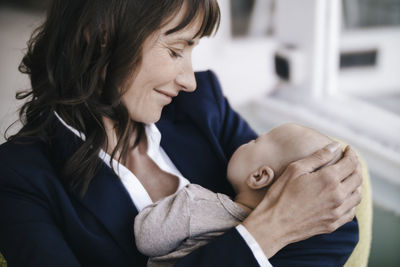 Businesswoman in cafe holding sleeping baby