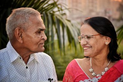 Close-up of senior couple face to face against palm leaf