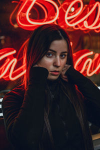 Portrait of beautiful young woman standing with red umbrella