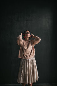 Portrait of young woman standing against wall